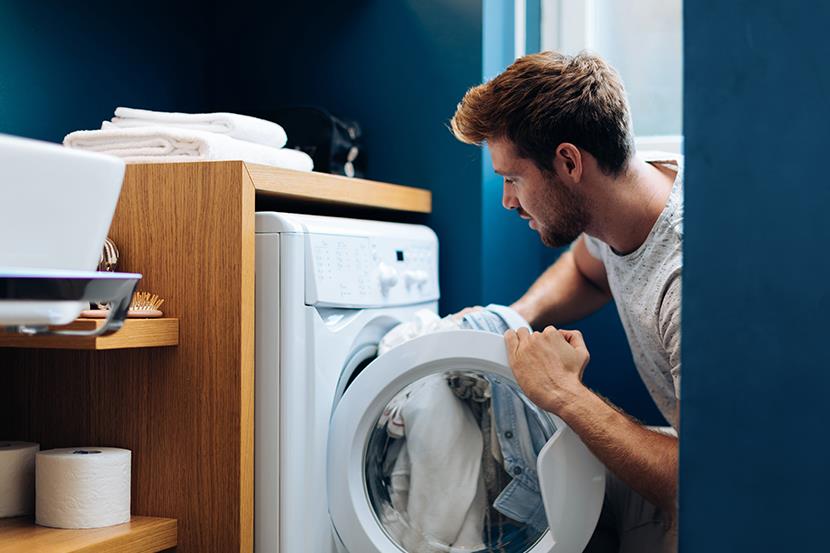 man putting laundry into dryer